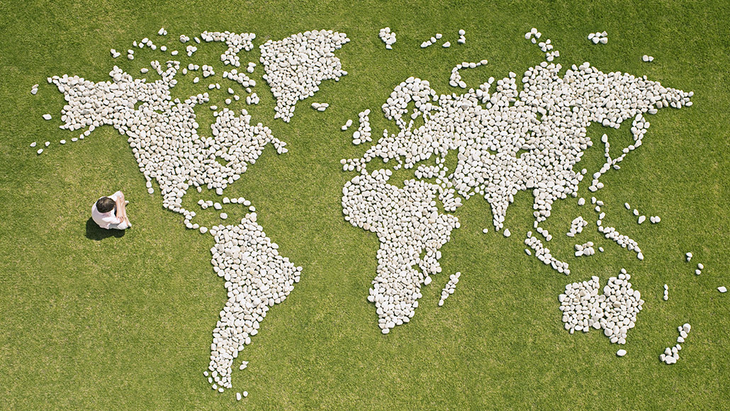 A boy sitting in front of a world map made from stones