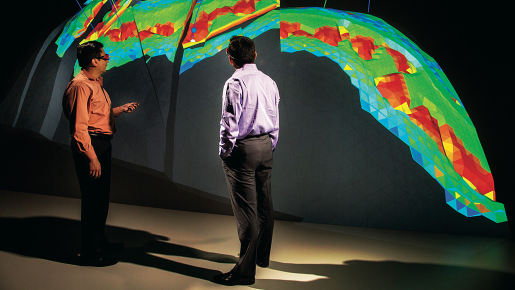 two men stand in front of seismic imaging readout